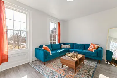 a living room with a blue couch and a table at Orange Oasis in the Heart of East Rock with FREE parking near DT and Yale in New Haven