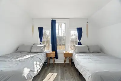 two beds in a room with blue curtains at Cozy Gem in the Heart of East Rock with FREE Parking near Yale and DT in New Haven
