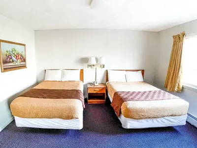 a hotel room with two beds and a window at Utica Rest Inn in Utica