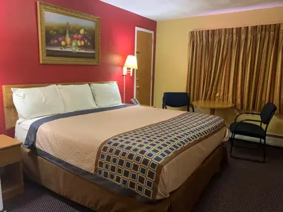 a hotel room with a bed and a red wall at Utica Rest Inn in Utica