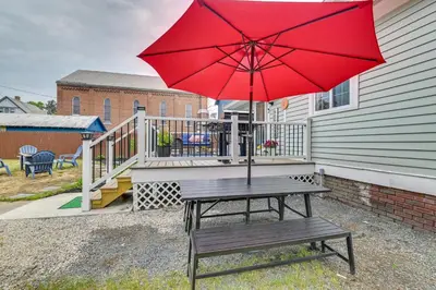 a picnic table with a red umbrella on a porch at Family-Friendly Glens Falls Home with Sun Porch in Glens Falls