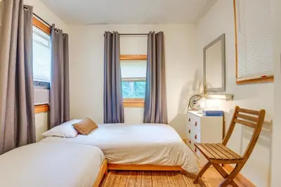 a bedroom with two beds and a chair at Storybook Stratton House 3 Mi to Mount Snow! in Stratton
