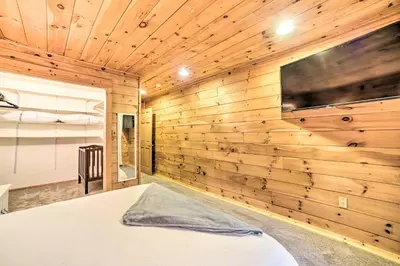 a bedroom with a wooden wall with a tv at Spacious Cabin with Decks Near Saratoga Springs in Middle Grove