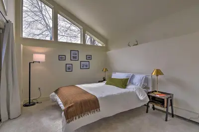 a bedroom with a large bed and two windows at Catskill Getaway on 6 Acres with Swimming Pond! in Liberty