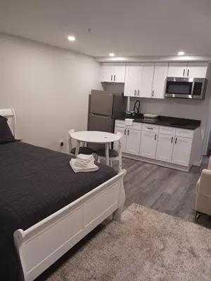 a bedroom with a bed and a kitchen with white cabinets at Fully Furnished Studio Wifi GYM Free Parking in Hartford
