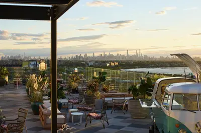 a rooftop patio with tables and chairs and a view of the city at Renaissance New York Flushing Hotel at Tangram in Queens