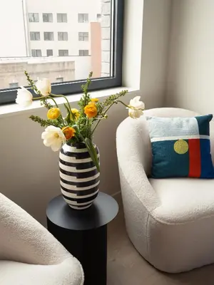 a vase of flowers sitting on a table next to a chair at Penny Williamsburg in Brooklyn