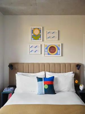 a bed with white pillows and paintings on the wall at Penny Williamsburg in Brooklyn