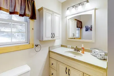 a bathroom with a sink and a mirror and a window at Swaying Pines in Wilmington
