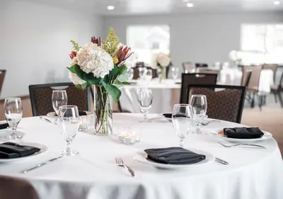a table with a white table cloth and a vase of flowers at Hotel One75 in Hamilton