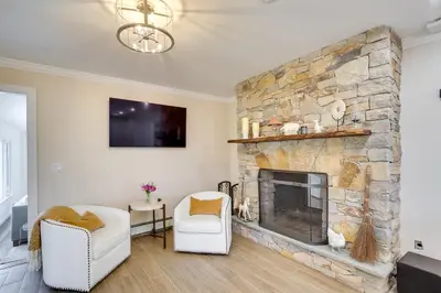 a living room with a stone fireplace and two white chairs at Lovely Highland Home with Pool and Hot Tub! in Highland