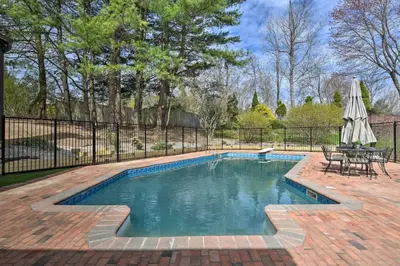 a swimming pool with a table and an umbrella at Lovely Highland Home with Pool and Hot Tub! in Highland