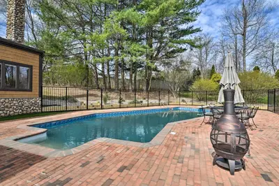 a swimming pool with a table and an umbrella at Lovely Highland Home with Pool and Hot Tub! in Highland