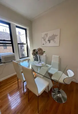 a dining room with a glass table and white chairs at 1BR Apt in Sunnyside 15 min to Manhattan in Woodside