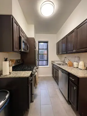 a large kitchen with black cabinets and a sink at 1BR Apt in Sunnyside 15 min to Manhattan in Woodside