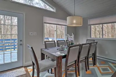 a dining room with a table and chairs and windows at 6 Mi to Camelback Slopes! Home with Game Room in Long Pond