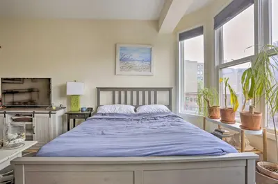 a bedroom with a bed with blue sheets and windows at Hoboken Studio Near Dining about 15 Min to NYC! in Hoboken