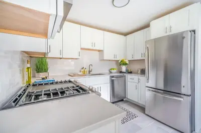 a kitchen with white cabinets and a stainless steel refrigerator at Beautiful Charming Cottage 4 min from Woodstock in Woodstock