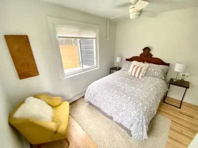 a bedroom with a bed and a chair and a window at Beautiful Charming Cottage 4 min from Woodstock in Woodstock