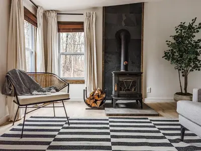 a living room with a fireplace and a chair and a stove at Pinewood Bungalow - Luxury Cabin, Kid-Friendly in Catskill