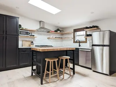 a kitchen with black cabinets and a stainless steel refrigerator at Pinewood Bungalow - Luxury Cabin, Kid-Friendly in Catskill