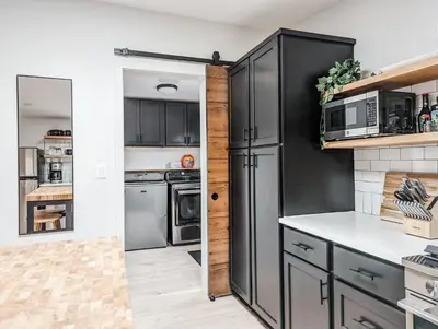 a kitchen with black cabinets and a black refrigerator at Pinewood Bungalow - Luxury Cabin, Kid-Friendly in Catskill