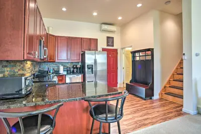 a kitchen with a refrigerator and two bar stools at half Mi to Windham Mtn Main Street Condo in Windham