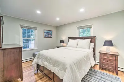a bedroom with a large bed and two windows at Family-Friendly Retreat with Hot Tub 1 Mi to Dtwn in Saratoga Springs