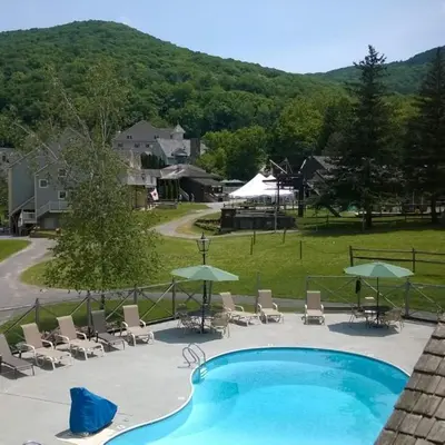 a swimming pool with chairs and umbrellas and a mountain at Disney Magic at Jiminy Mountain in Hancock