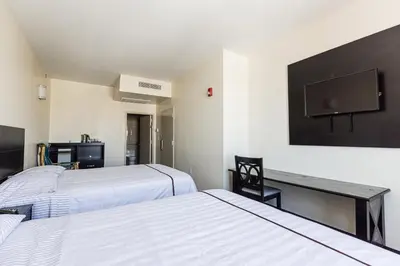 a room with two beds and a desk and a tv at Astoria Inn LaGuardia Hotel in Queens