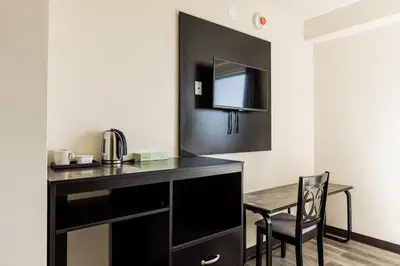 a room with a desk with a chair and a mirror at Astoria Inn LaGuardia Hotel in Queens