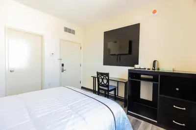 a bedroom with a bed and a desk and a tv at Astoria Inn LaGuardia Hotel in Queens