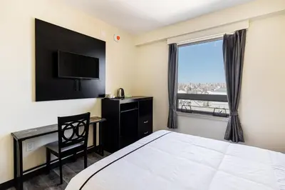a bedroom with a bed and a desk and a window at Astoria Inn LaGuardia Hotel in Queens