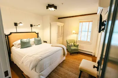a bedroom with a bed and a green chair at Hill Farm Inn - Manchester in Sunderland