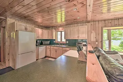 a kitchen with wooden cabinets and a white refrigerator at Lakefront Gloversville Home with Beach and Dock! in Broadalbin