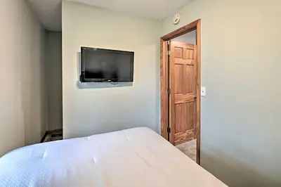 a bedroom with a bed and a flat screen tv on a wall at Lakefront Gloversville Home with Beach and Dock! in Broadalbin