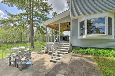 a porch with chairs and tables on a house at Lakefront Gloversville Home with Beach and Dock! in Broadalbin