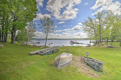 a group of boats in a grassy field next to a lake at Lakefront Gloversville Home with Beach and Dock! in Broadalbin