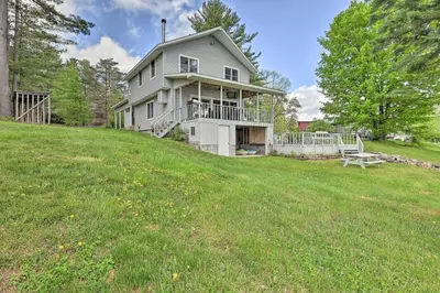 a house on top of a hill with a yard at Lakefront Gloversville Home with Beach and Dock! in Broadalbin