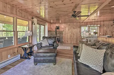 a living room with leather furniture and wood paneling at Lakefront Gloversville Home with Beach and Dock! in Broadalbin