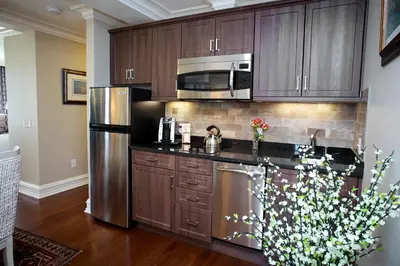 a kitchen with wooden cabinets and a stainless steel refrigerator at Guest House at Norwalk Inn in Norwalk