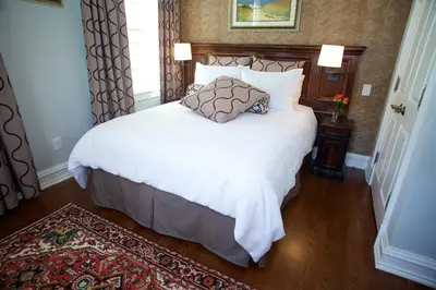 a bedroom with a white bed with a pillow on it at Guest House at Norwalk Inn in Norwalk