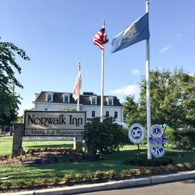 a building with two flags in front of it at Guest House at Norwalk Inn in Norwalk