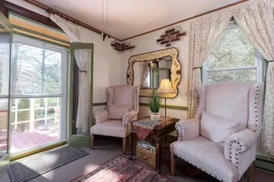 a living room with two chairs and a mirror at Saratoga Farmstead B&B in Saratoga Springs