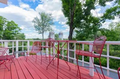 a deck with red chairs and a table on it at Saratoga Farmstead B&B in Saratoga Springs