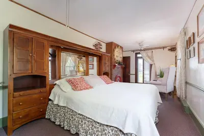 a bedroom with a large white bed and a dresser at Saratoga Farmstead B&B in Saratoga Springs