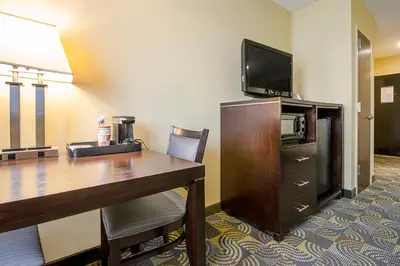 a hotel room with a desk and a flat screen tv at Quality Inn & Suites Glenmont - Albany South in Glenmont