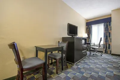 a hotel room with a table and a tv and chairs at Quality Inn & Suites Glenmont - Albany South in Glenmont