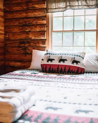 a bed in a log cabin with a pillow on it at Afton Cabin in Afton