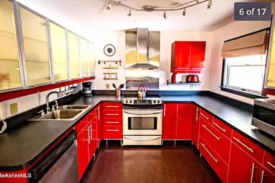 a kitchen with red cabinets and a stove top oven at Gorgeous Ski On/Off 2 BR Sleeps 8 Jiminy-Must See Luxury in Hancock